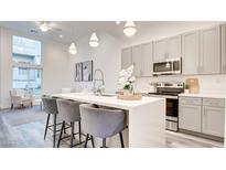 Bright kitchen with a quartz countertop island, stainless steel appliances and gray cabinets at 1157 Blossom Point St, Las Vegas, NV 89135