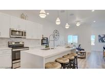 Modern kitchen boasts white cabinets, stainless steel appliances, and an island with bar seating at 1181 Blossom Point St, Las Vegas, NV 89135