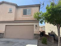 Two-story house featuring a two car garage, desert landscaping, and beige stucco siding at 2105 William Holden Ct, Las Vegas, NV 89142