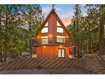 Charming cabin with a-frame design and multiple windows surrounded by lush greenery and offering mountain views at 2160 Via Vita St, Mount Charleston, NV 89124