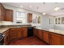 Warm kitchen featuring wood cabinets, granite countertops, stainless steel appliances, and wood flooring at 240 Jumping Springs Pl, Henderson, NV 89012