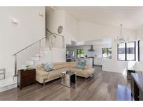 Bright living room featuring wood floors, modern staircase, and open layout into the kitchen area at 2712 Sidonia Ave, Las Vegas, NV 89102