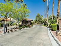 Gated community entrance with mature trees and lush landscaping under a bright blue sky at 4567 Madreperla St, Las Vegas, NV 89121