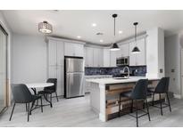 Modern kitchen features stainless steel appliances, gray cabinets, and a stylish breakfast bar with unique wood accents at 689 Principle Point Ave, Henderson, NV 89012