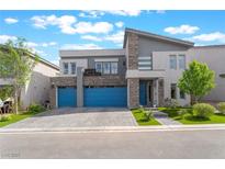 Contemporary two-story home featuring blue garage doors and stone accents at 7307 Grace Estate Ave, Las Vegas, NV 89113
