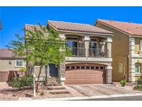 Inviting two-story home featuring a charming balcony, stone accents, and a well-manicured front yard at 7732 Canon Walk St, Las Vegas, NV 89139