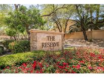 Inviting community entrance sign amidst lush landscaping and vibrant red flowers at 1742 Sand Storm Dr, Henderson, NV 89074