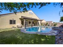 Backyard featuring a sparkling pool, covered patio, and lush green lawn at 8125 Turbys Treehouse Pl, Las Vegas, NV 89131