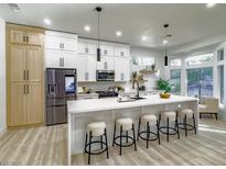 Bright, updated kitchen with white cabinets, a large island with seating, and modern stainless steel appliances at 10709 Hunters Woods Pl, Las Vegas, NV 89134