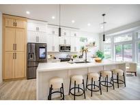 Bright kitchen with stainless appliances, light wood floors, white cabinets, and a large center island with seating at 10709 Hunters Woods Pl, Las Vegas, NV 89134