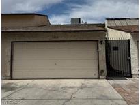 View of the garage door of a one-story home with a black metal gate to the right at 1203 Mews Ln, Las Vegas, NV 89101