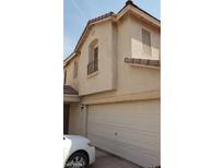 Beige two-story home featuring a two-car garage, balcony and desert landscaping at 10282 Keystone Pastures St, Las Vegas, NV 89183