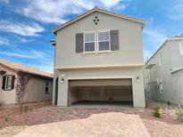 Two-story home with an open garage and brick driveway, with a light-grey color scheme and shuttered windows at 4274 Tarim St, Las Vegas, NV 89147