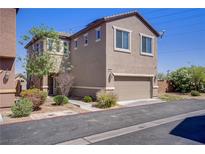 Two-story home featuring a two-car garage and simple xeriscaped yard with bushes and a young tree at 626 Taliput Palm Pl, Henderson, NV 89011
