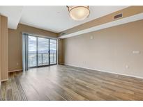 Bright living room featuring wood floors, neutral walls, and sliding glass doors with a city view at 8255 S Las Vegas Blvd # 1404, Las Vegas, NV 89123