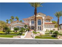Elegant stucco home featuring a tile roof, lush landscaping, and a grand entrance with steps and tropical trees at 8838 Spanish Mountain Dr, Las Vegas, NV 89148