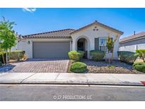 Charming single-story home with a tile roof, landscaped yard, and brick-paved driveway leading to a two-car garage at 9431 S Tee Pee Ln, Las Vegas, NV 89178