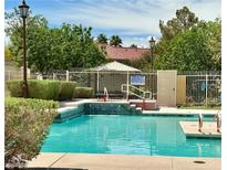 Community pool with clear blue water and adjacent lounge area, perfect for relaxation and recreation at 1753 Tanner Cir, Henderson, NV 89012