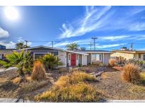 Charming single-story home featuring a red front door and desert landscaping under a bright, sunny sky at 2129 N Michael Way, Las Vegas, NV 89108