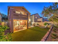 Inviting backyard with artificial grass, covered patio, outdoor furniture, and landscaped borders at 6546 American Flower St, Las Vegas, NV 89148