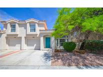 Charming two-story home featuring a two-car garage, a vibrant blue front door, and mature desert landscaping at 1000 Grammy Dr, Las Vegas, NV 89145
