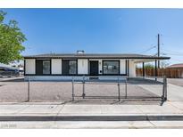 Charming single story home featuring fresh white paint, black trim, gravel yard, and chain link fence at 3040 Carroll St, North Las Vegas, NV 89030