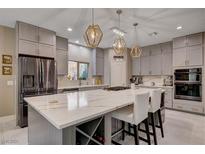 Bright kitchen with white marble countertops, stainless steel appliances, gray cabinetry, and decorative pendant lighting at 7613 Pulpit Rock Ct, Las Vegas, NV 89166