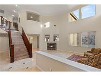 Bright living room with a staircase, fireplace, high ceilings, and several windows that provide lots of natural light at 1265 Vietti St, Henderson, NV 89012