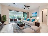 Bright living room with stylish furnishings, a ceiling fan, and a sliding glass door to the sunroom at 8732 Kendall Brook Cir, Las Vegas, NV 89149