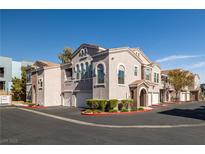 View of the exterior of the apartment complex with tan stucco, red trim, and a row of garages at 10001 Peace Way # 2228, Las Vegas, NV 89147