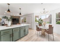 Bright, open kitchen featuring a green island with seating and an adjacent dining area at 7932 Diamond Rock Way # 101, Las Vegas, NV 89128