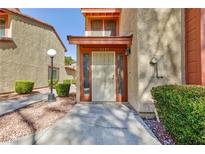 Inviting home exterior featuring a well-kept yard, stucco facade, and charming front entrance with security gate and address number at 2405 Pickwick Dr # 55, Henderson, NV 89014