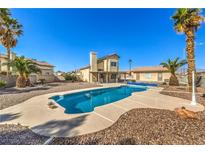 Inviting backyard featuring a private pool, palm trees, and desert landscaping, perfect for outdoor living at 3708 Calumet Farm Cir, North Las Vegas, NV 89031