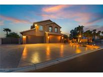 Stunning two-story home with a spacious driveway and three-car garage, lit by landscape and home exterior lighting at 4200 Scott Peak Ct, Las Vegas, NV 89129