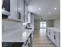 Modern kitchen featuring white cabinets, countertops, stainless steel appliances, and wood flooring at 5800 Balzar Ave, Las Vegas, NV 89108