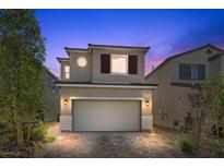 Charming two-story home featuring a two-car garage, and brick paved driveway at dusk at 6626 Evander St, North Las Vegas, NV 89086