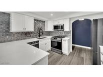 Modern kitchen features white cabinets, stainless steel appliances, and a stylish backsplash at 8408 White Eagle Ave # 101, Las Vegas, NV 89145