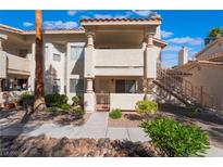Inviting condo exterior with a gated front patio, mature landscaping and stairway to the upper unit at 912 Falconhead Ln # 101, Las Vegas, NV 89128