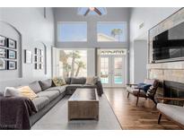 Bright living room featuring a gray sectional sofa, high ceilings, and a fireplace with a stone surround at 3079 Paseo Mountain Ave, Henderson, NV 89052