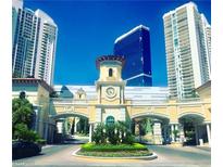 Elegant community entrance featuring manicured landscaping, clock tower, and views of high-rise buildings against a clear blue sky at 2857 Paradise Rd # 305, Las Vegas, NV 89109