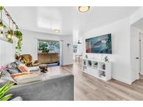 Bright living room featuring a large window, gray sofa, wooden floors, and wall-mounted television at 3151 Soaring Gulls Dr # 2136, Las Vegas, NV 89128