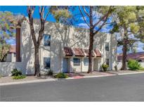 Charming townhome featuring a stucco facade, red tile accents, and mature landscaping at 611 Spyglass Ln, Las Vegas, NV 89107