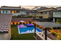 Stunning backyard featuring a sparkling pool, integrated spa, stylish pergola, and built-in outdoor kitchen, perfect for entertaining at 11954 Camden Ridge Ct, Las Vegas, NV 89138