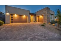 Modern home showcasing a driveway with a three car garage featuring stylish doors and beautiful stone accents at 11954 Camden Ridge Ct, Las Vegas, NV 89138