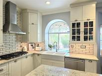 Bright kitchen featuring white cabinets, subway tile backsplash, and stainless steel appliances, with a view from the sink at 2434 Amoretti St, Henderson, NV 89052