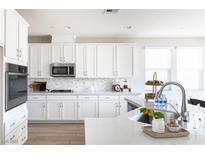 Bright kitchen features white cabinetry, stainless steel appliances, and a gorgeous backsplash at 16 Cresta Villa Ct, Henderson, NV 89011