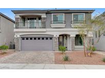 Two-story home with a two-car garage, balcony, stone accents, and well-maintained landscaping at 6618 Tangled Vines Ave, Las Vegas, NV 89139