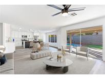 Bright open-concept living room with a ceiling fan, sliding glass door, and view of the backyard pool at 9541 Summersweet Ct, Las Vegas, NV 89123