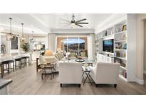 Spacious living room with built-in shelves, neutral decor, and an open floor plan with views of the outside at 12217 Tempestad Ave, Las Vegas, NV 89138