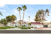 Elegant home featuring a red tile roof, lush landscaping, a circular driveway, and mature palm trees at 2101 Diamond Bar Dr, Las Vegas, NV 89117